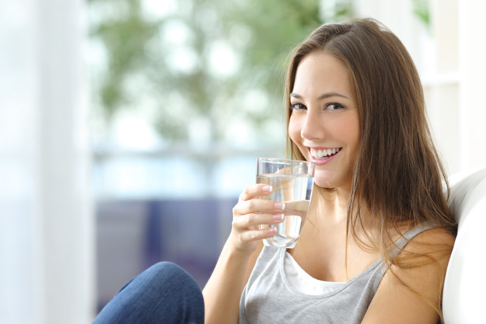 Girl drinking water from glass with water filter