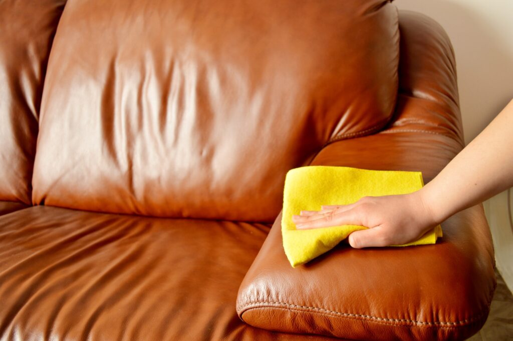Person wiping a sofa with a cloth, showing why some furniture should not be cleaned with water.