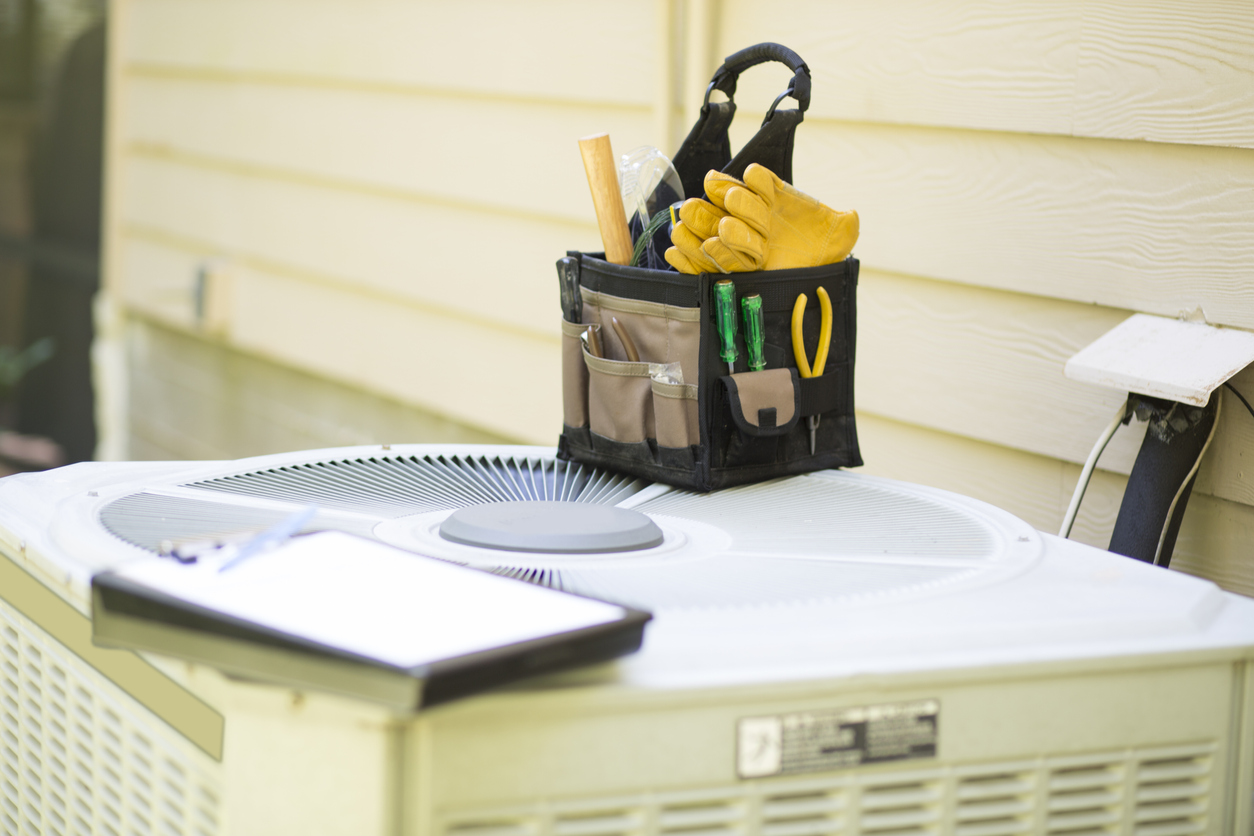 Technician performing maintenance on an air conditioning unit outdoors.