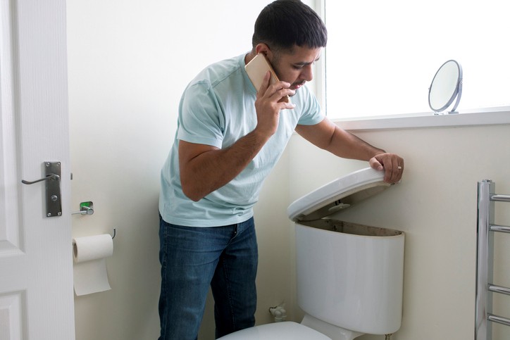 Man on phone having a toilet plumbing problem