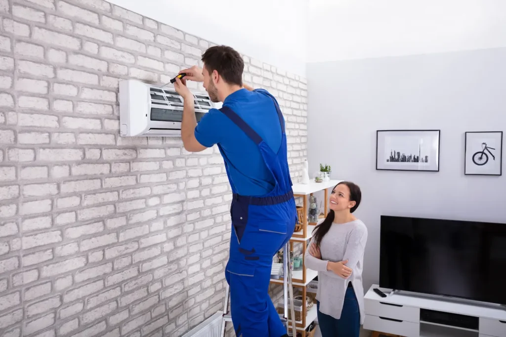 Male Technician Repairing Air Conditioner With Screwdriver