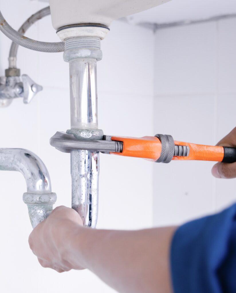 Plumber working in the bathroom, plumbing repair service, repairing leaking sinks with adjustable wrench, assemble and install concept.