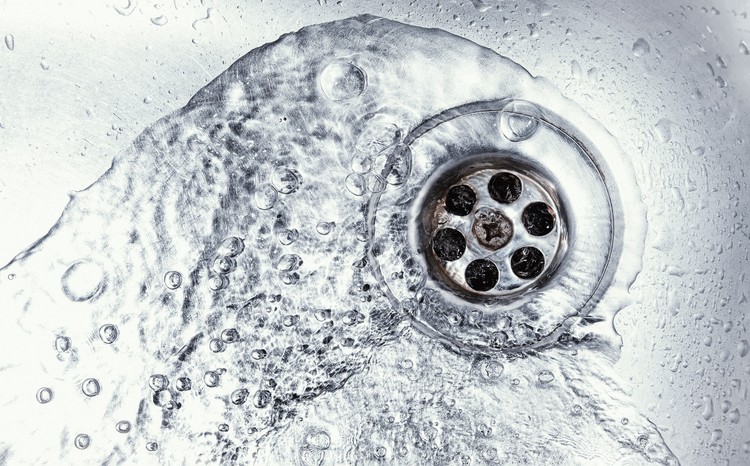 Sink with running water illustrating the benefits of fall drain cleaning