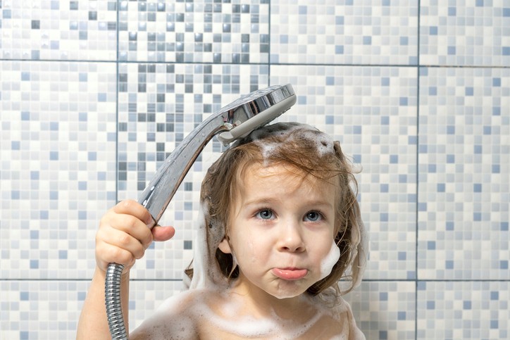 Baby girl taking a shower with concern over frozen pipes affecting water flow in winter