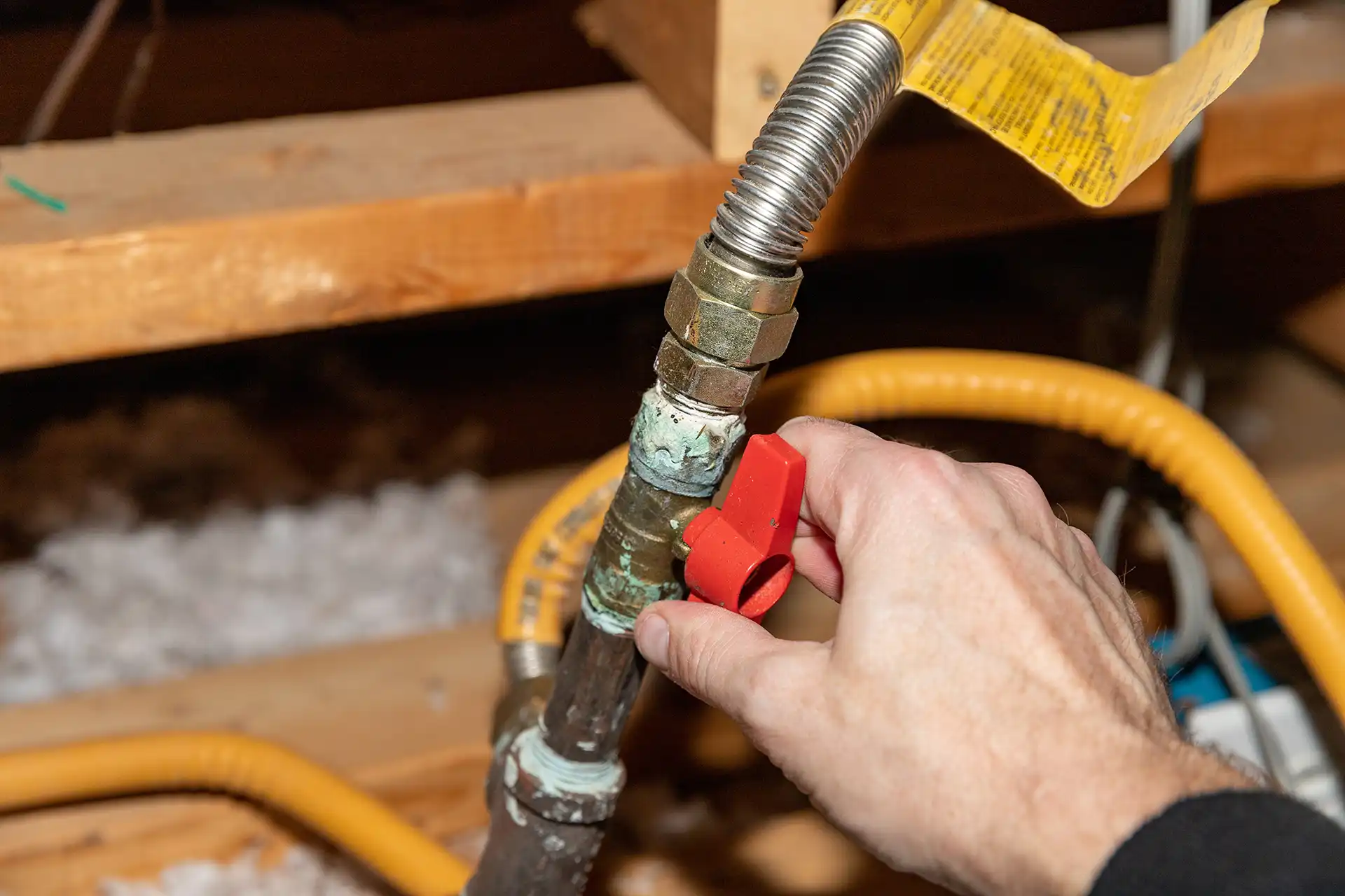 Technician turning red shutoff valve on flexible gas line