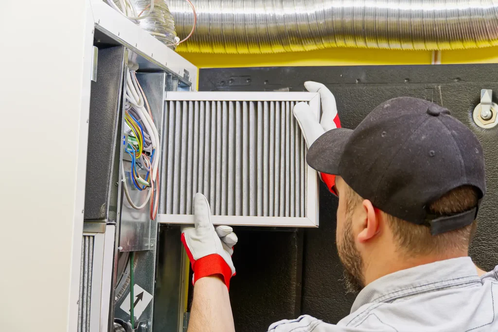 HVAC technician performing heating system tune-up by replacing air filter