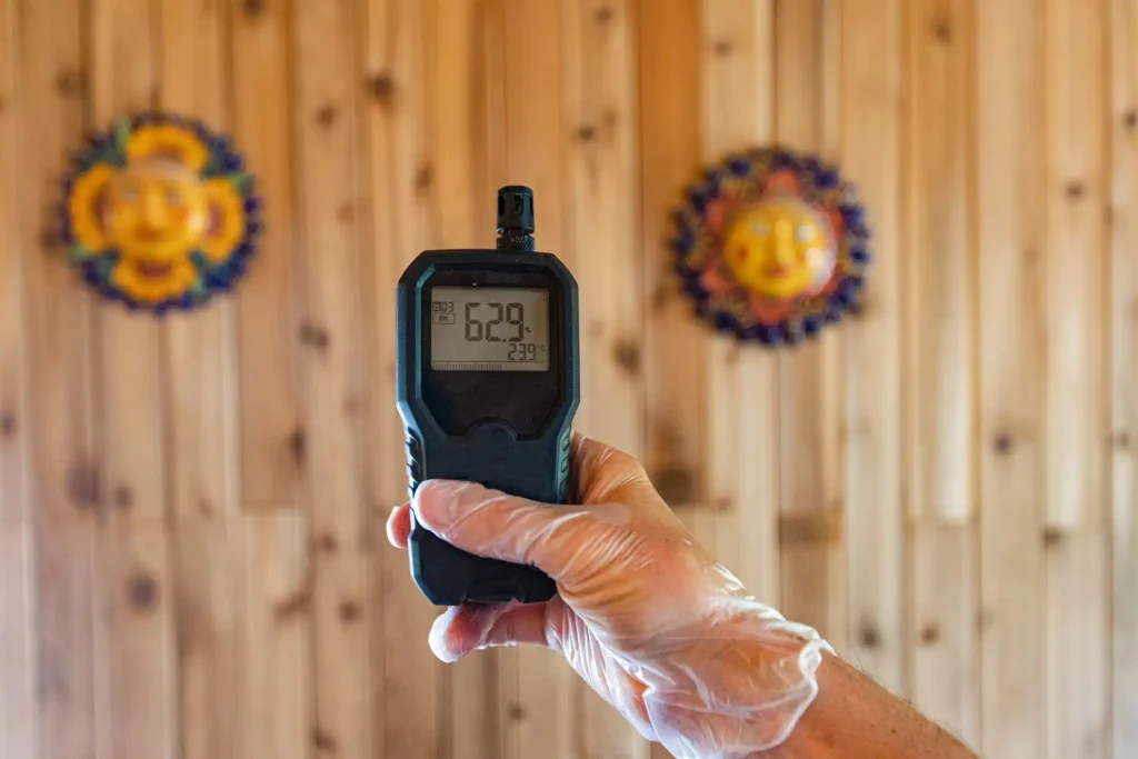 Technician holding indoor air quality testing device showing temperature and humidity readings
