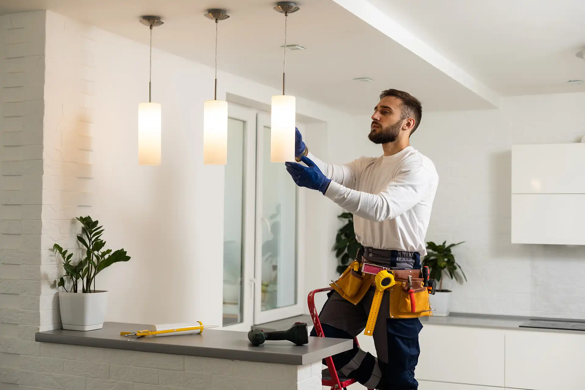 Electrician installing pendant lights in modern home kitchen
