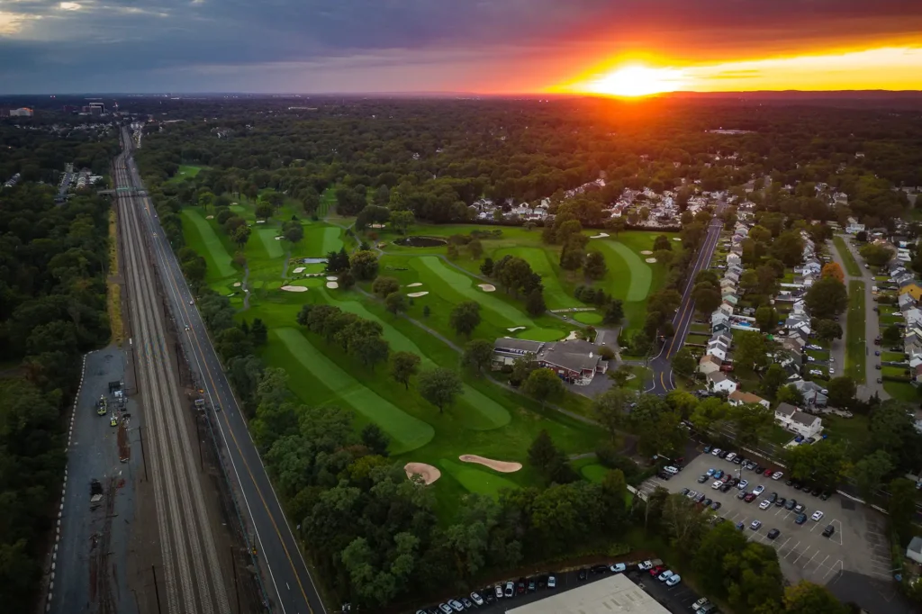 Aerial view of Colonia, New Jersey at sunset with a golf course and railroad tracks