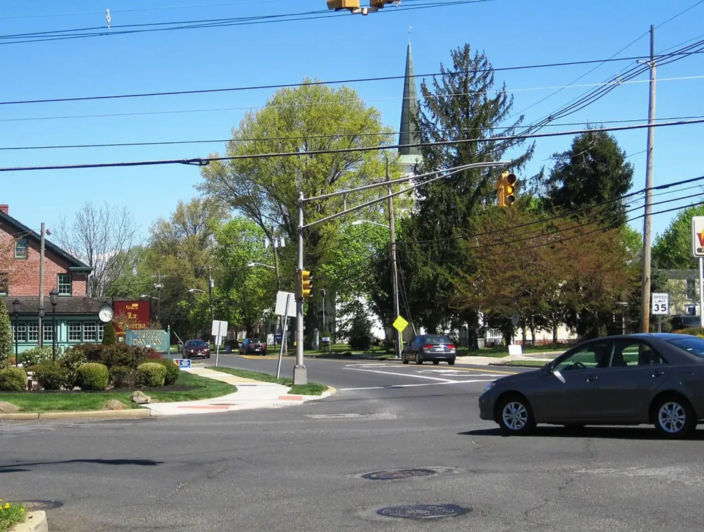 Downtown street intersection in Dayton, New Jersey with shops, traffic lights, and a church steeple